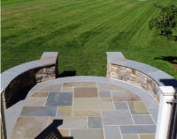 This sitting wall was designed for a client in Katonah, NY. The circular motif of the sitting walls and the bluestone terrace were designed to tie into the lines of the residence. The sitting wall is constructed of fieldstone and topped with a 2” rock-faced, bluestone cap. Note the decorative bluestone outline of the terrace, which accentuates the curved line of the walls. 