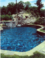 This spectacular kidney shaped pool in South Salem was designed to nestle into the rocky terrain. The natural setting dictated the natural shape of the pool and the native stone construction materials. The coping is constructed of irregular shaped grey granite. Note the use of the plant materials to soften the stone edges and whimsical sculpture to enhance the experience. 