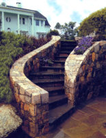 The undulating line of this set of stairs beckons the visitor to climb to the next level at this home in Westport, CT. Constructed of fieldstone with bluestone treads, the stairs wind upwards from the patio to the upper garden. Note the built-in planter in the stair wall. 