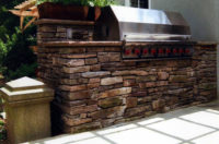 This custom-designed outdoor built-in grill was constructed for a client in Westport, CT using earth-tone fieldstone for the walls and matching 2”, rock-face, fieldstone coping. Counters on either side of the grill allow for food prep. Note the electrical outlet for appliance use. 