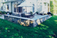 This cottage in Greenwich, CT includes this charming patio with fieldstone sitting wall capped with rodeface chiseled bluestone.
